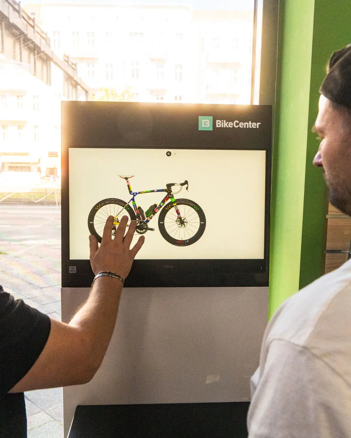 Konfigurator-Bildschirm im Laden, eine Hand wählt ein Rennrad aus